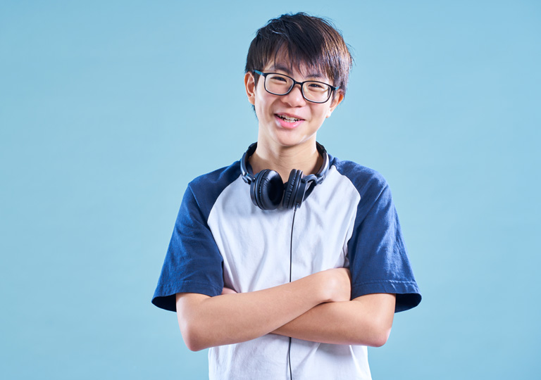 young tween smiling in front of light blue background